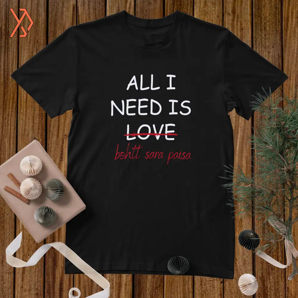 Black t-shirt with text 'ALL I NEED IS LOVE' on a wooden surface with decorative items.