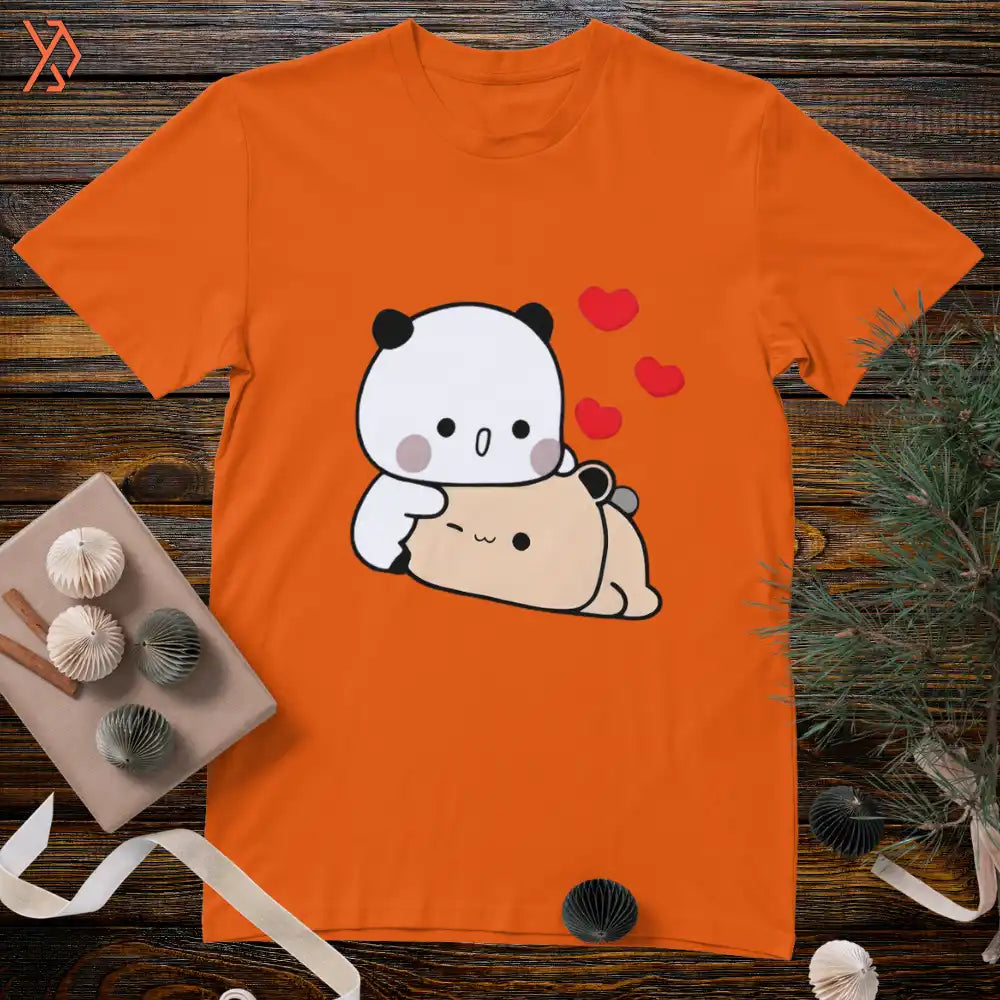 Orange t-shirt with a cartoon panda and bear design on a wooden surface. yourdora.pk